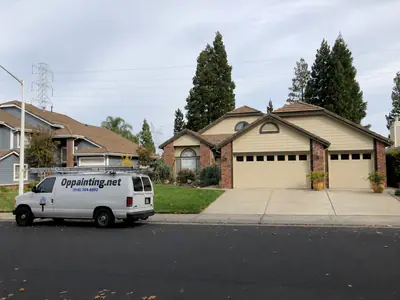 The same Roseville home after the repaint, with the siding, gable vents and garage doors finished in cream against the brick.