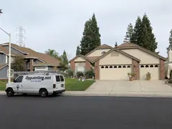 A single-storey Roseville home with brick facing and two garage doors before the repaint, with the company van parked at the kerb, an extension ladder on its roof rack and paint pails set out on the lawn.
