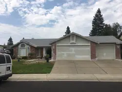 A single-storey Roseville home part-way through an exterior repaint, with primer patched over filled areas on both garage doors and plastic masking taped down the brickwork and around the trim.