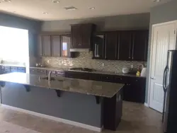 The same Folsom kitchen finished, with the walls in grey-green and the island repainted grey. The espresso cabinets, granite countertops and mosaic backsplash were masked off and left as they were.