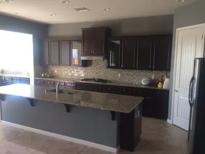 The same Folsom kitchen finished, with the walls in grey-green and the island repainted grey. The espresso cabinets, granite countertops and mosaic backsplash were masked off and left as they were.