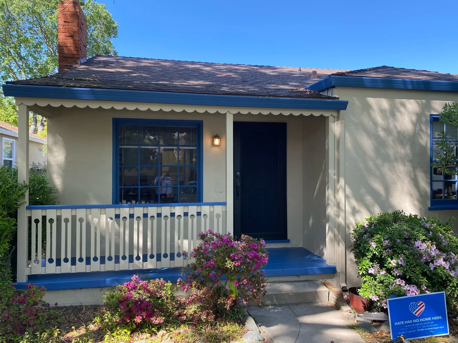 Cottage-Style Home with Blue Trim and Hate Has No Home Here Yard Sign