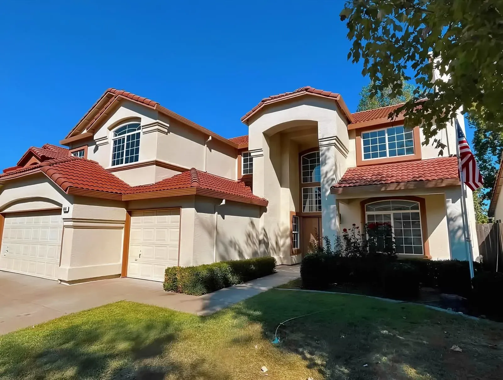 Modern Two-Story Stucco Home with Red Tile Roofing and American Flag